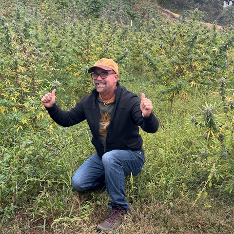 Emerald Farm Tours guest poses with cannabis plants on a farm